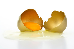 Broken gold egg on white background.